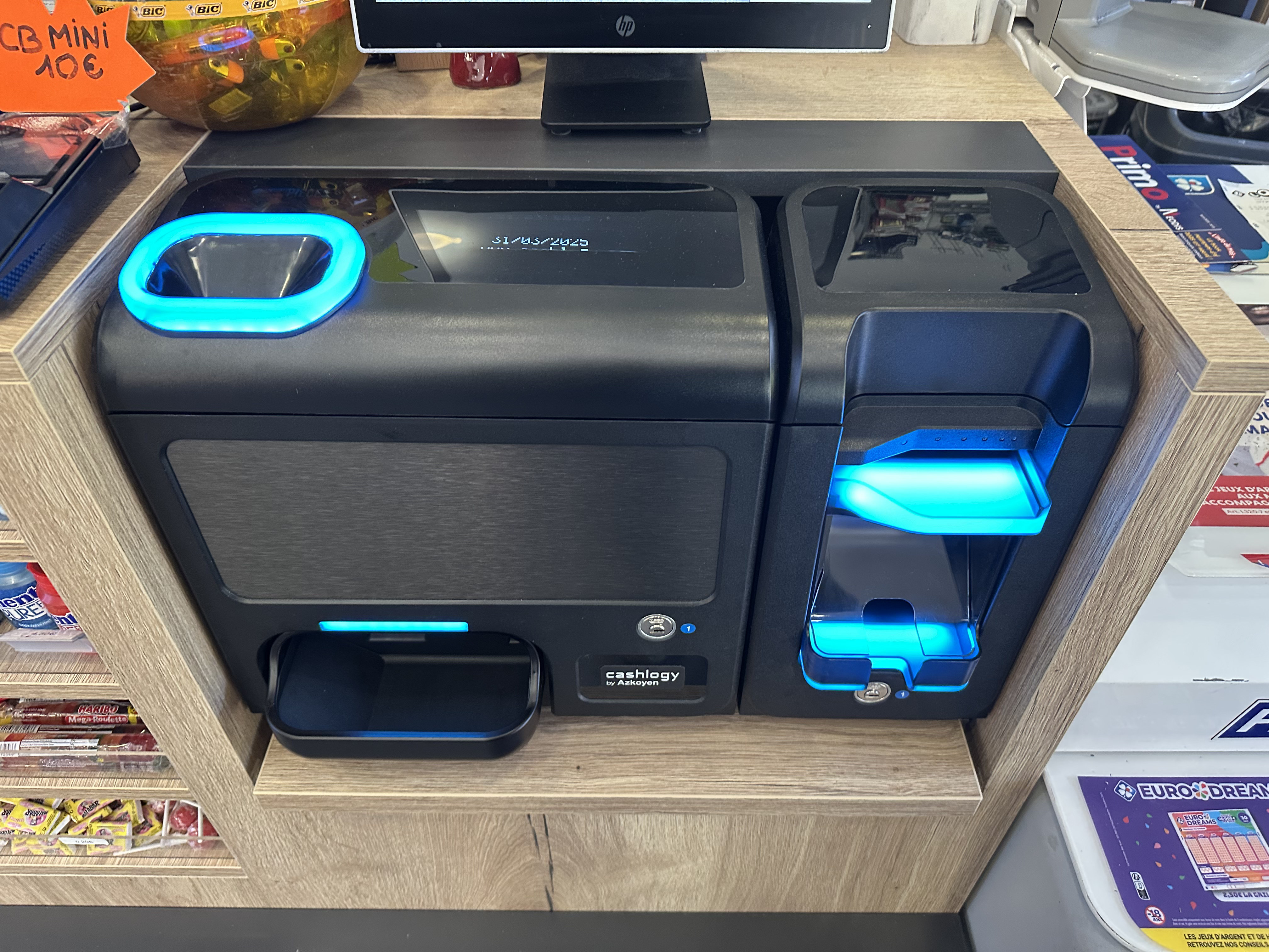 Gros plan monnayeur Cashlogy intégré dans un comptoir – lumières bleues
